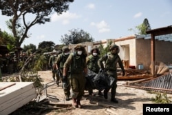 以色列士兵在以色列南部Kibbutz Kfar Aza地区抬着被巴勒斯坦武装分子杀害的以色列平民的遗体。（2023年10月10日）