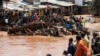 Wakazi wa kitongoji cha Mathare wakisimama karibu na nyumba zilizoharibiwa na mafuriko, kufuatia mvua kubwa mjini Nairobi, Aprili 24. Picha ya AFP