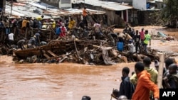 Wakazi wa kitongoji cha Mathare wakisimama karibu na nyumba zilizoharibiwa na mafuriko, kufuatia mvua kubwa mjini Nairobi, Aprili 24. Picha ya AFP