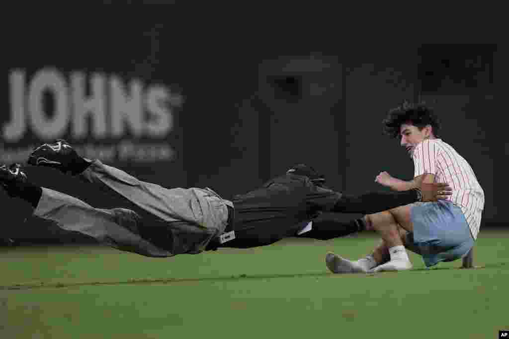 A fan who ran on to the field is tackled by a Truist Park security guard in the eight inning of a baseball game between St. Louis Cardinals and Atlanta Braves, Sept. 5, 2023, in Atlanta, Georgia.