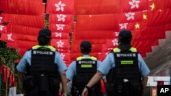 香港警察在香港主权移交中国27年纪念日走过挂满中国国旗和香港旗帜的街道。（2024年7月1日）