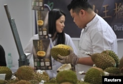 资料照：中国广西壮族自治区南宁举行的马来西亚榴莲节的促销员在猫山王榴莲摊位前工作。 （2017年11月4日）
