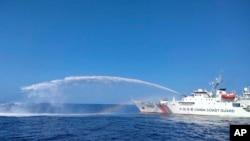 资料照片：2023年12月9日，在菲律宾海警提供的照片中，一艘中国海警船(右)对菲律宾渔业和水产资源局的一艘船动用水炮，该船当时正在接近有争议的南中国海的岛屿。(美联社照片)