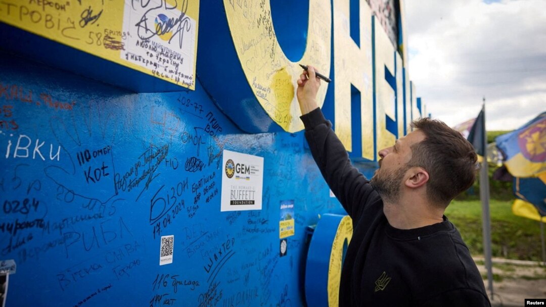 Ukraine President Volodymyr Zelenskiy signs a road sign in Donetsk region, Ukraine, April 19, 2024. (Ukrainian Presidential Press Service/Handout via Reuters)