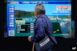 台湾强震后，东京一名男子驻足观看日本一家电视台播放对冲绳地区的海啸警报。(2024年4月3日)