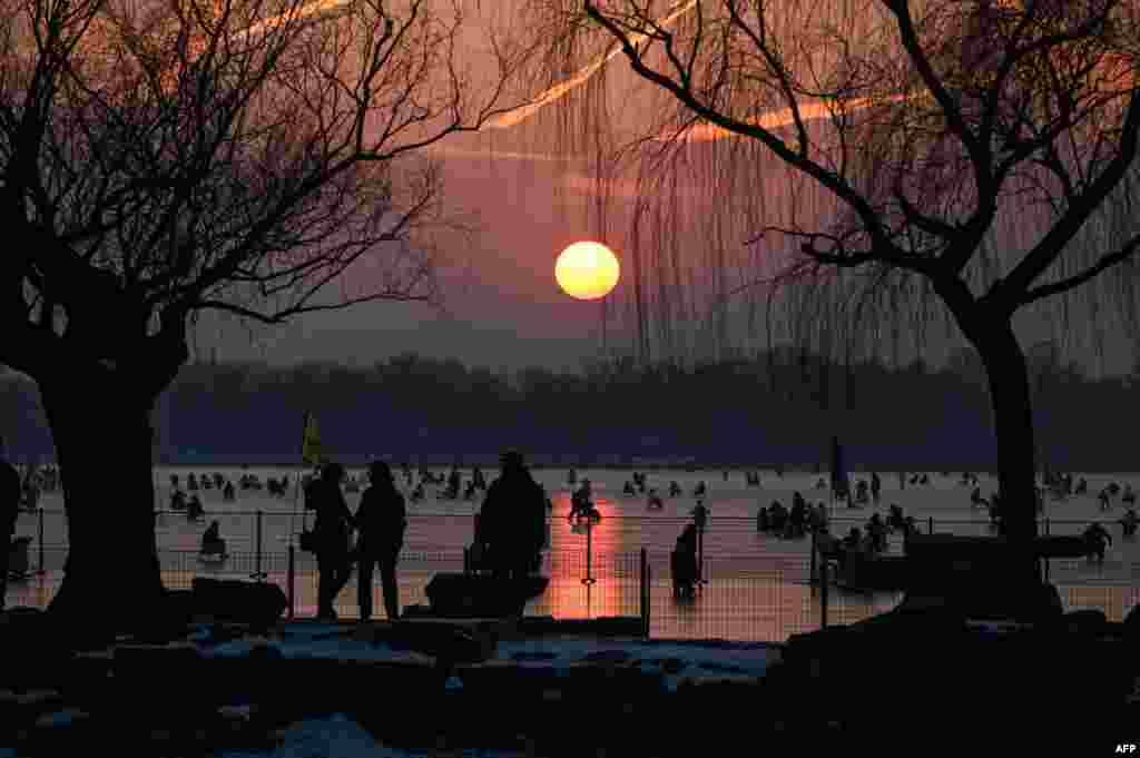 People ride sleds on a frozen lake at the Summer Palace during sunset in Beijing.
