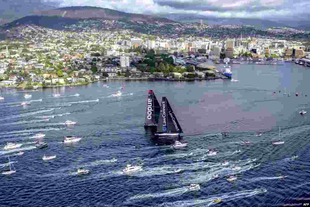 Yachts Law Connect and Andoo Comanche approach the finish line of the annual Sydney to Hobart yacht race in Hobart. (AFP Photo/Rolex/Andrea Francolini)