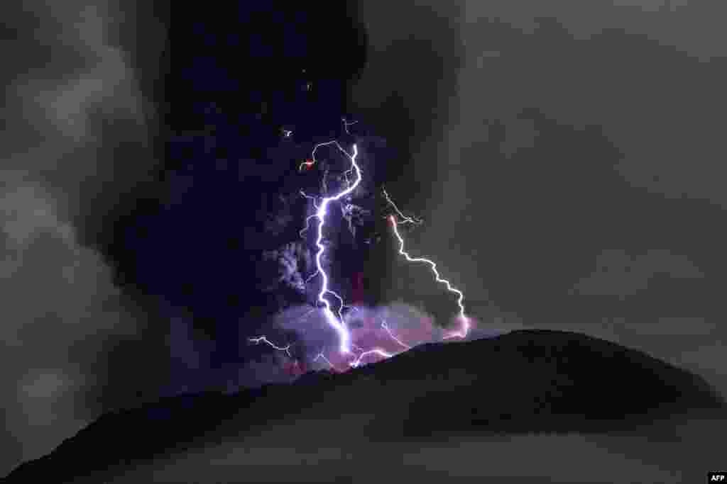 This handout picture taken and released on May 18, 2024 by the Indonesian Geological Agency shows Mount Ibu spewing volcanic ash as lightning strikes, as seen from the monitoring post in West Halmahera, North Maluku.