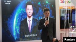 在中国浙江嘉兴乌镇举办的第五届世界互联网大会(WIC)博期间，新华社新闻主播邱浩在搜狗展台上站在以他为原型的人工智能虚拟新闻主播旁边。（资料照片，2018年11月7日）
