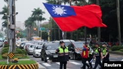 台湾警察护送一名举着台湾旗帜的男子走过台北街头。（2024年5月24日）