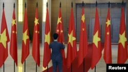 资料照：一名男子在越南国会大厦内整理中越两国国旗准备迎接中国领导人习近平的到访。（2015年11月6日）