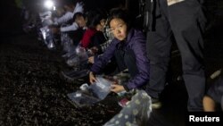 资料照片: 2023年4月3日美国得克萨斯州弗龙顿: 一名从墨西哥格兰德河偷渡进入美国的中国妇女将自己的物品放入塑料袋