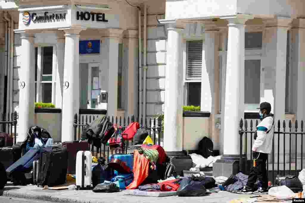 A man believed to be an asylum-seeker stands outside of a hotel in protest at the condition of his accommodation, in London, Britain.
