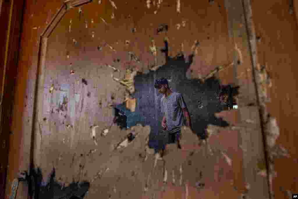 A Kashmiri, inspecting a house where suspected rebels had taken refuge, is seen through a hole created by a mortar shell fired by government forces during a gunfight, in Srinagar, Indian controlled Kashmir.