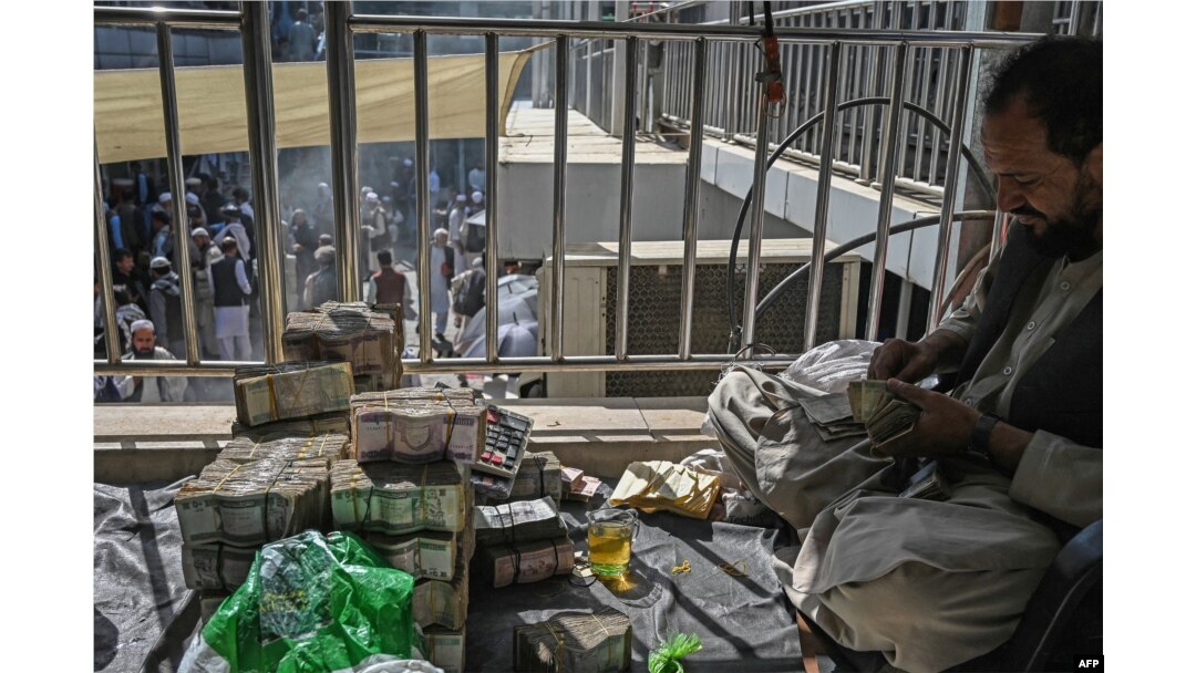 FILE - Afghan currency exchange dealers carry out their tasks after the money exchange market reopens for business in Kabul, Sept. 5, 2021.