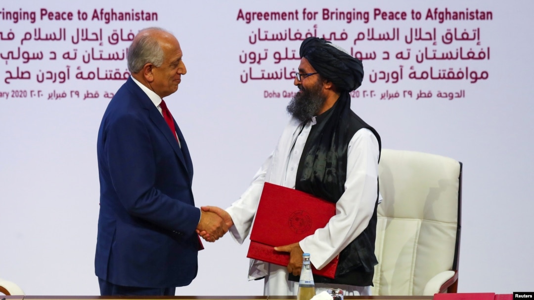 FILE - Mullah Abdul Ghani Baradar, leader of the Taliban delegation, and Zalmay Khalilzad, U.S. envoy for peace in Afghanistan, shake hands after signing an agreement between members of Afghanistan's Taliban and the U.S. in Doha, Qatar, Feb. 29, 2020.