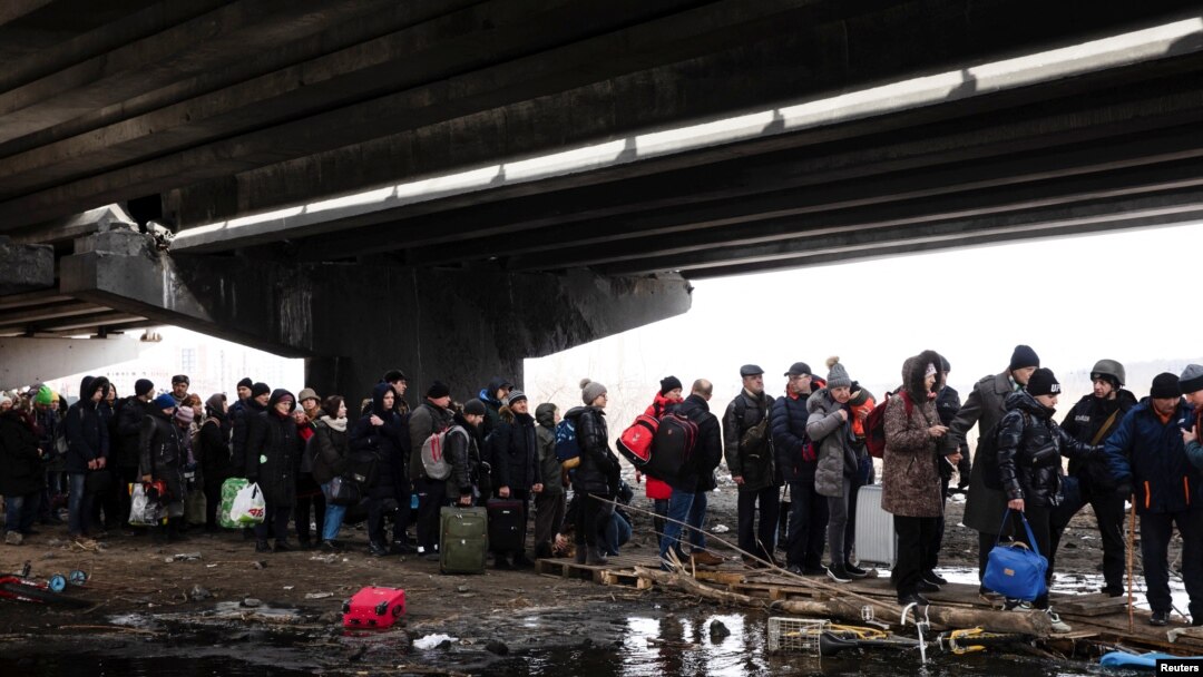 People flee under a destroyed bridge to cross the Irpin River, in Irpin outside Kyiv, Ukraine, March 9, 2022. 