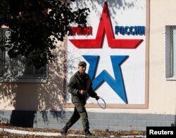 Російський військовослужбовець проходить повз штаб Оперативної групи російських військ у Тирасполі, столиці сепаратистського регіону Придністров’я Молдови, 3 листопада 2021 року. На банері написано «Армія Росії». REUTERS/Глеб Гаранич