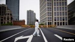 2022年5月18日，在中国上海，COVID-19 爆发期间，一名身穿防护服的工人在封锁期间走在封闭的桥上。（路透社）