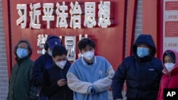 资料照：北京市民在宣传习近平法治思想的标语墙前排队等候接受核算检测。（2022年12月5日）
