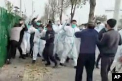 中国河南郑州富士康代工厂里身穿防护服的警察和保安殴打参加示威活动的工人。(2022年11月23日)