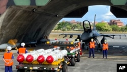 资料照片：台湾军队士兵站在F16V战机前，准备进行装载美制AGM-84鱼叉反舰导弹及AIM-120和AIM-9空空导弹的训练。（2022年9月16日）