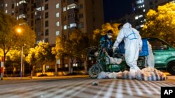 上海封城后，一名快递员将食物袋送到一个住宅小区大门外。（2022年4月11日）