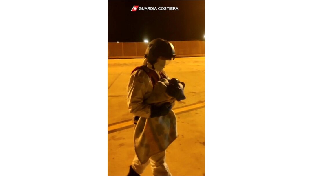 An Italian coast guard member holds a child who was evacuated from the Spanish ship Open Arms after being rescued from the Mediterranean Sea, Nov. 12, 2020, in Malta.