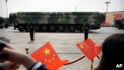 资料照片--2019年10月1日，北京，纪念中华人民共和国成立70周年的阅兵式上，携带DF-41弹道导弹的军车驶过，观众挥舞着中国国旗。