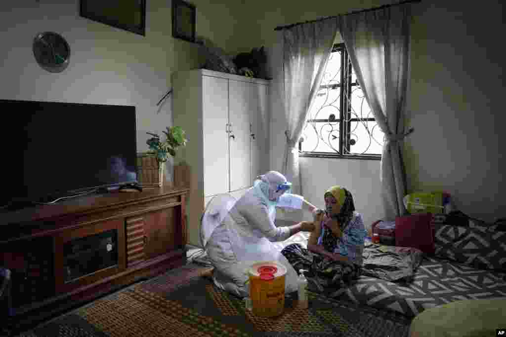 A nurse administers a Pfizer COVID-19 vaccine to an elderly woman in her house in rural Sabab Bernam, central Selangor state, Malaysia.