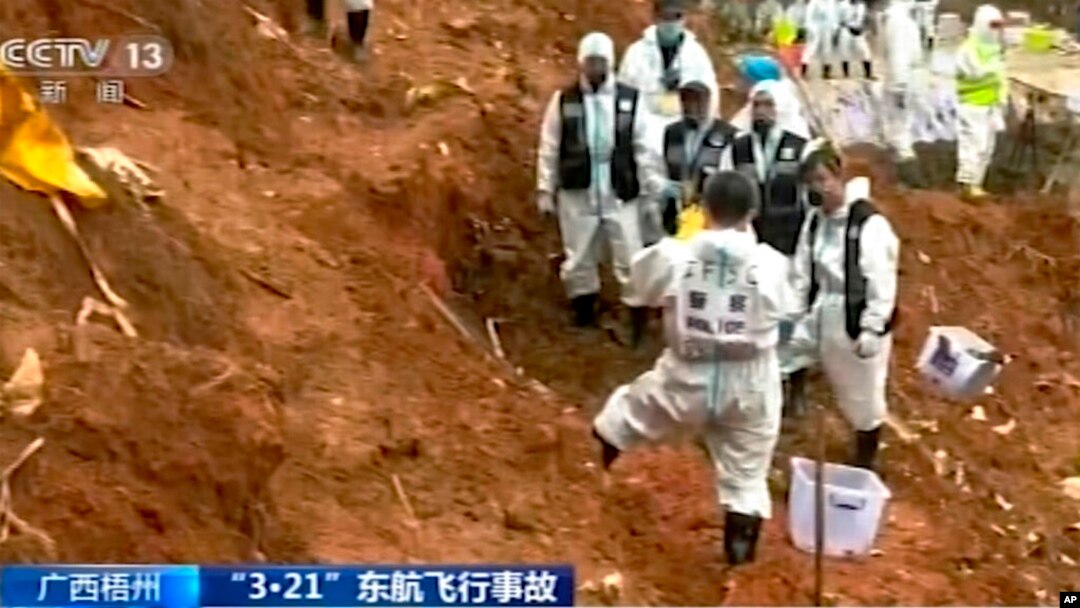 In this image taken from video footage run by China's CCTV, search-and-rescue workers stand at the area where they recovered the second orange-colored "black box" at the China Eastern flight crash site in Tengxian County, March 27, 2022, in southern China