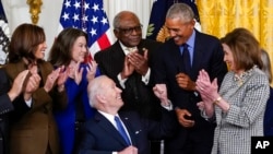 President Joe Biden looks to former President Barack Obama after signing an executive order during an event about the Affordable Care Act, in the East Room of the White House in Washington, April 5, 2022. 