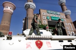 中国警察2008年10月8日在乌鲁木齐一所清真寺前搭乘装甲车执勤。