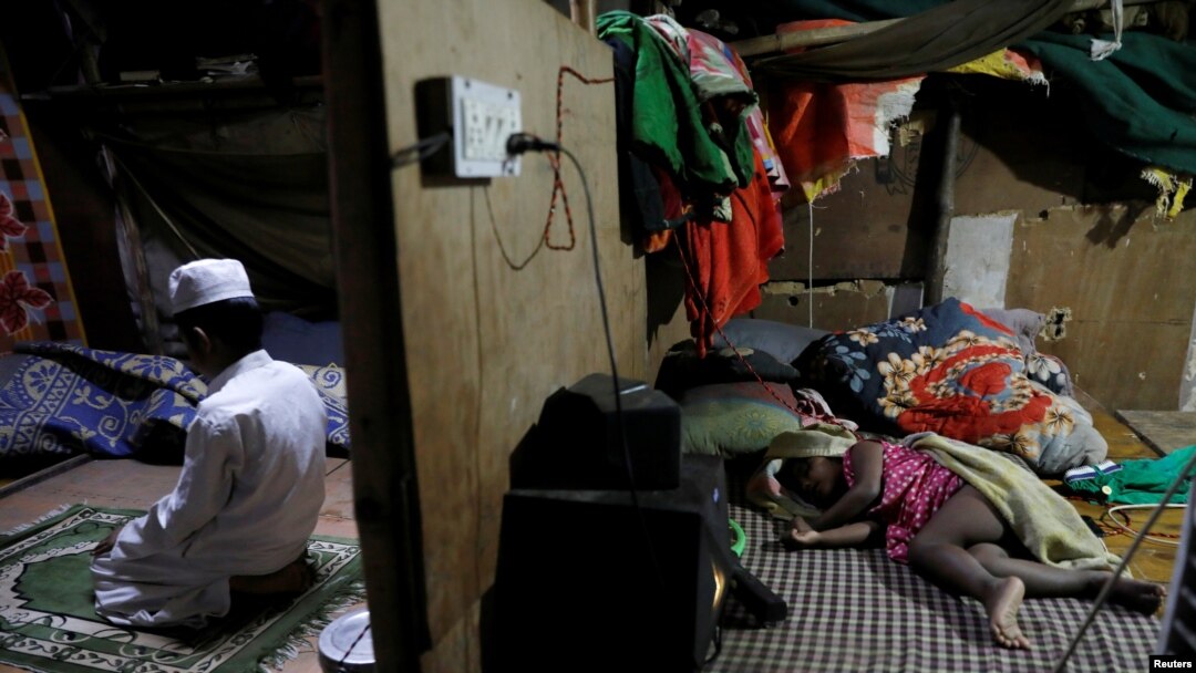 FILE - Rohingya refugee Shahid Hussain, 10, offers prayers after Iftar (breaking fast) time as his sister Sania, 2, sleeps in the next room at their house in a camp.
