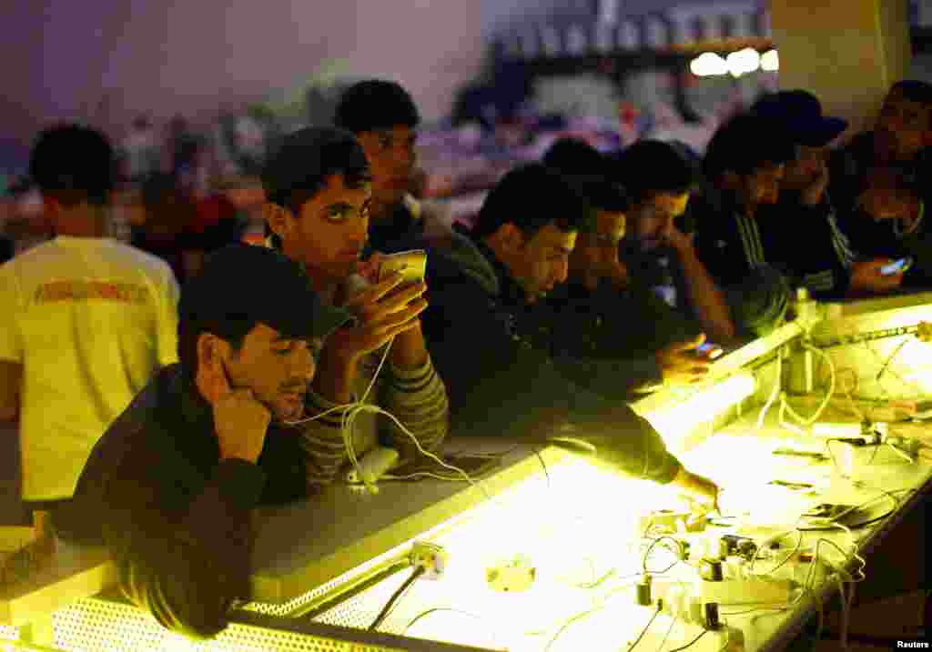 Migrants charge their mobile devices at an improvised shelter inside a concert hall in Wiesen, Austria, Sept. 13, 2015. (Reuters)