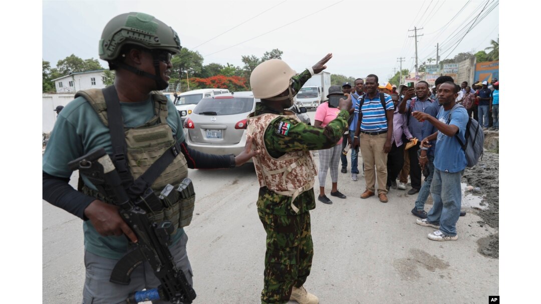 A Kenyan police officer takes photos of a group of Haitians welcoming the officers in Port-au-Prince, Haiti, on July 3, 2024.