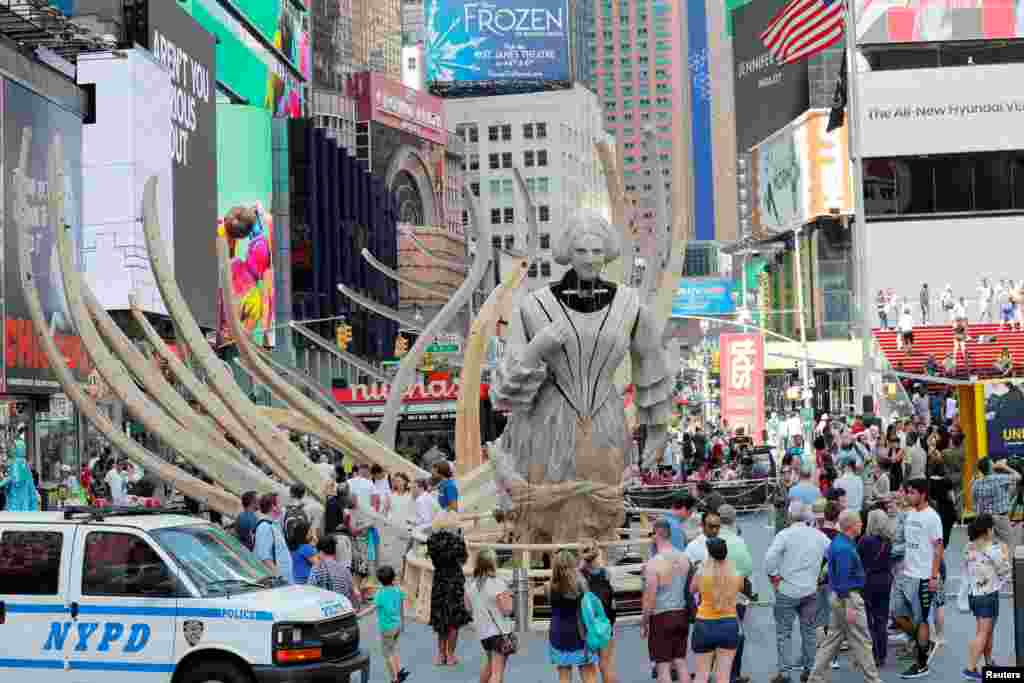 Pedestrians walk past artist Mel Chin's mixed reality climate change-themed art installation, "Unmoored," in the Times Square neighborhood of New York, July 11, 2018.