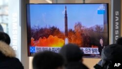 2022 年1月6日，在韩国首尔火车站的新闻节目中，人们在电视上观看显示朝鲜发射导弹图像的电视。（美联社）。