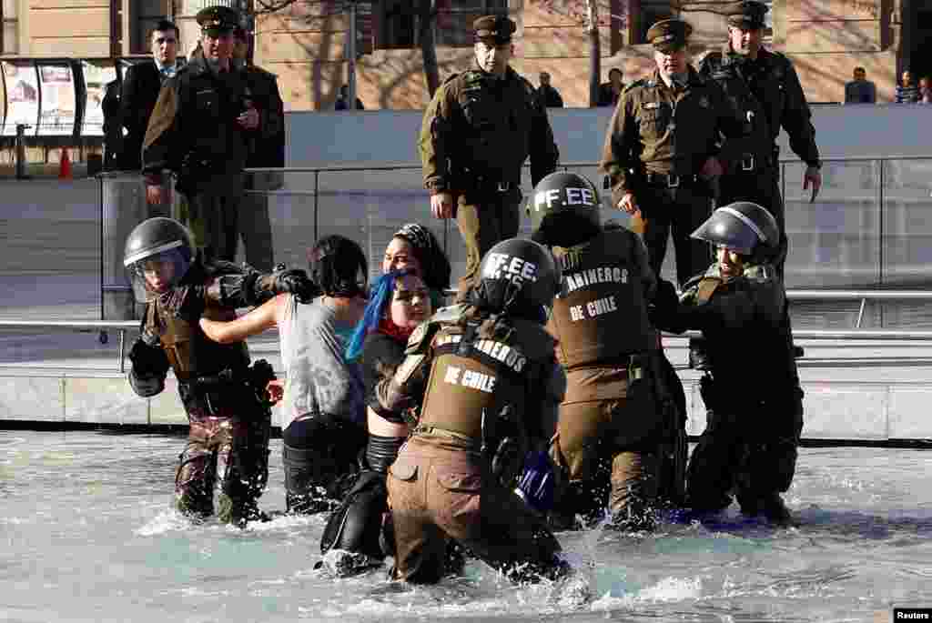 Mapuche Indian activists clash with riot police inside of a pool in front of the government palace during a protest to demand justice for indigenous Mapuche inmates in Santiago, Chile, June 27, 2018.