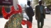 FILE - Pedestrians pass a wire and beaded rooster on display outside the Market Theater, background, in Johannesburg's Newtown cultural district, July 30, 2009. 