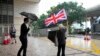A pro-democracy activist holds the British flag as pro-democracy activists charged with subversion arrive for an appearance in court in Hong Kong, Sept. 23, 2021.