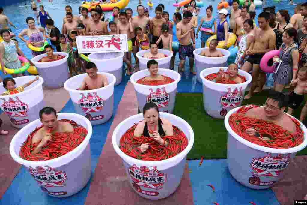 Participants take a bath in barrels filled with chili peppers during the Spicy Barrel Challenge contest inside a water park in Chongqing, China, July 7, 2018.