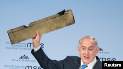 Israeli Prime Minister Benjamin Netanyahu holds up a remnant of what he said was a piece of Iranian drone which was shot down in Israeli airspace during his speech at the Munich Security Conference, Germany, Feb. 18, 2018. 