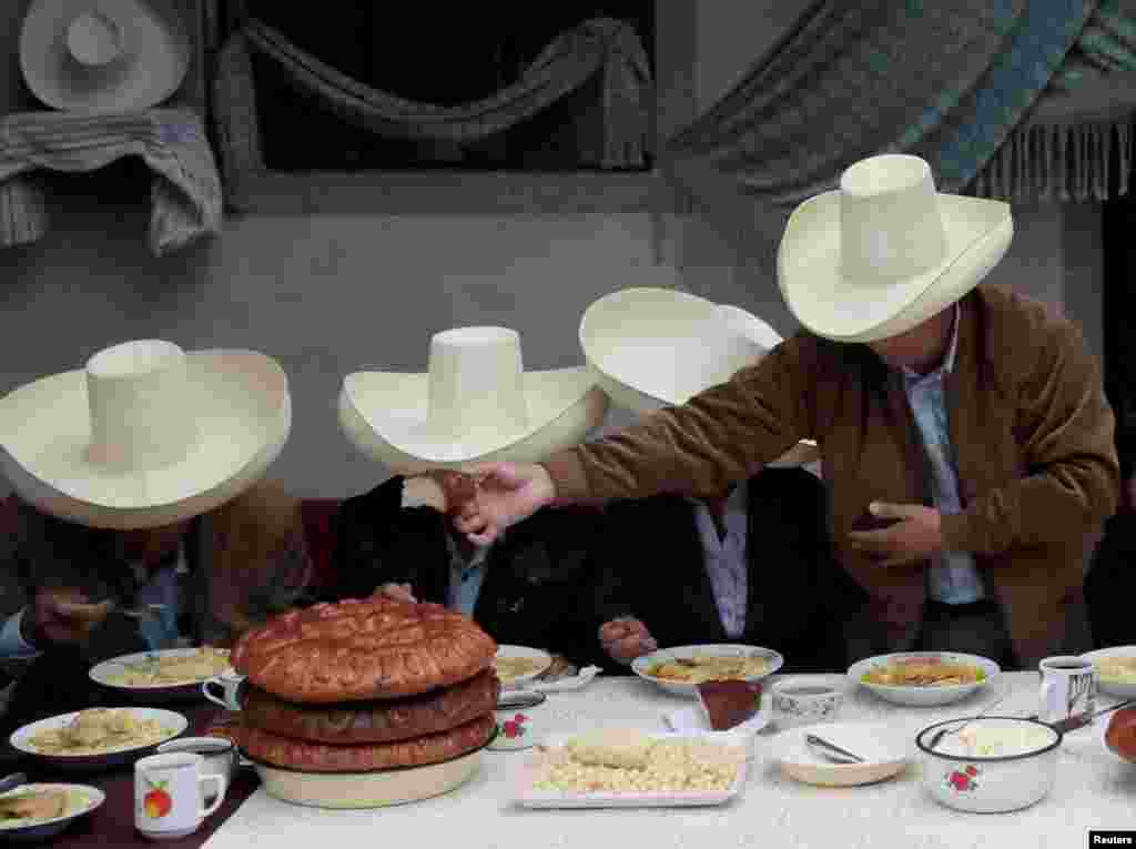 Peru's presidential candidate Pedro Castillo (R) hands over bread during a breakfast with members of his family before casting his vote in Chugur.