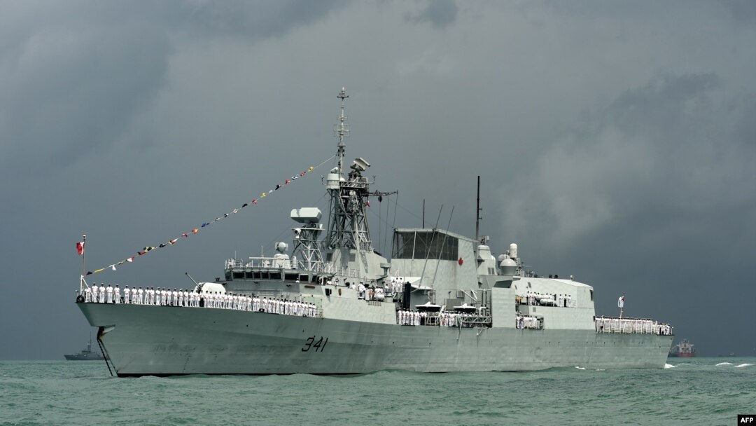 FILE - Crew members onboard the Royal Canadian Navy Halifax-class frigate, HMCS Ottawa wave along the strait near Changi Naval Base in Singapore, May 15, 2017. 