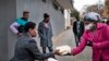A volunteer for the grassroots charity Hope for Vrededorp reaches out to a woman with a container of home-cooked food, at a daily food distribution in the impoverished district of Vrededorp in Johannesburg, April 28, 2020. 