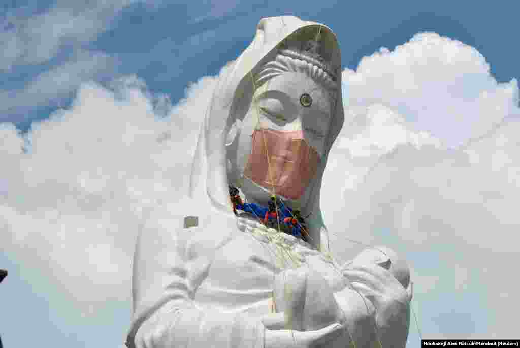 Workers place a mask on a 57-meter-tall Buddhist goddess statue to pray for the end of the COVID-19 pandemic at Houkokuji Aizu Betsuin in Aizuwakamatsu, Fukushima Prefecture, Japan.