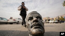 Боєць опозиції біля поваленого пам'ятника Хафезу Асаду в Дамаску, 8 грудня 2024 року