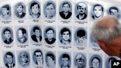 A man looks at a banner with pictures of Serbs killed by Bosnian forces during the 1992-95 Bosnian war in the Srebrenica area, in downtown Belgrade, Serbia, July 10, 2017.