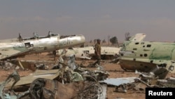 FILE - A Syrian Democratic Forces (SDF) fighter walks near destroyed airplane parts inside Tabqa military airport after taking control of it from Islamic State fighters, west of Raqqa city, Syria, April 9, 2017.